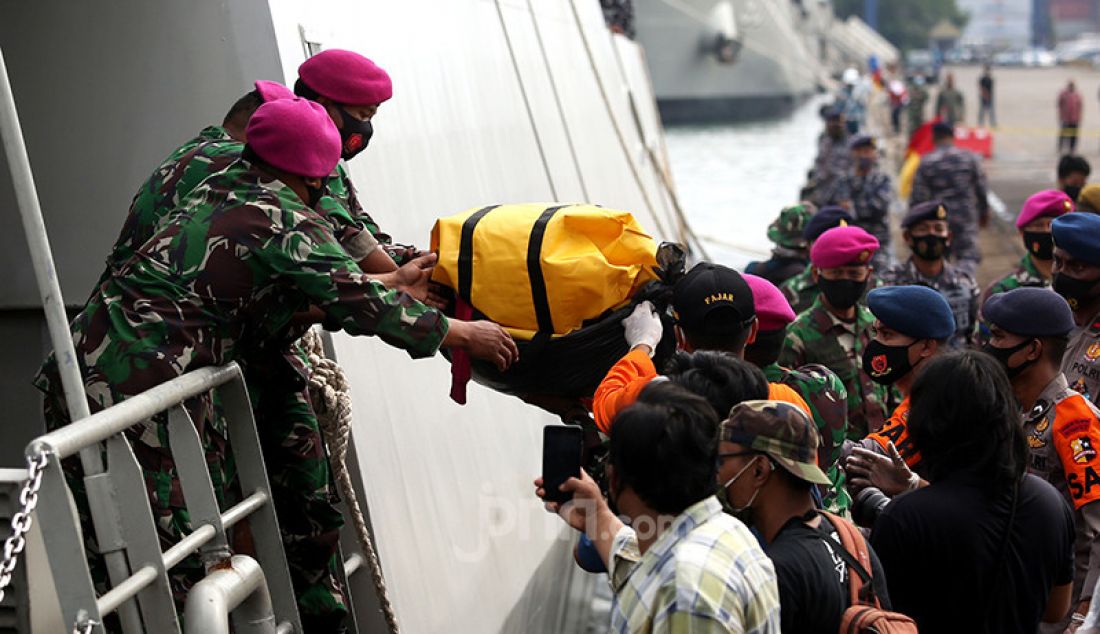 Anggota TNI dari kesatuan Marinir saat menurunkan serpihan pesawat Sriwijaya Air SJ 182 dan kantong jenazah yang berhasil dievakusi ke Dermaga, JICT 2, Jakarta, Minggu (10/1). - JPNN.com