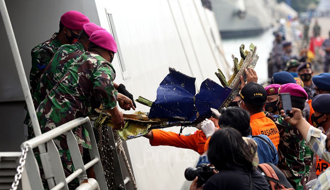 Anggota TNI dari kesatuan Marinir saat menurunkan serpihan pesawat Sriwijaya Air SJ 182 dan kantong jenazah yang berhasil dievakusi ke Dermaga, JICT 2, Jakarta, Minggu (10/1). - JPNN.com