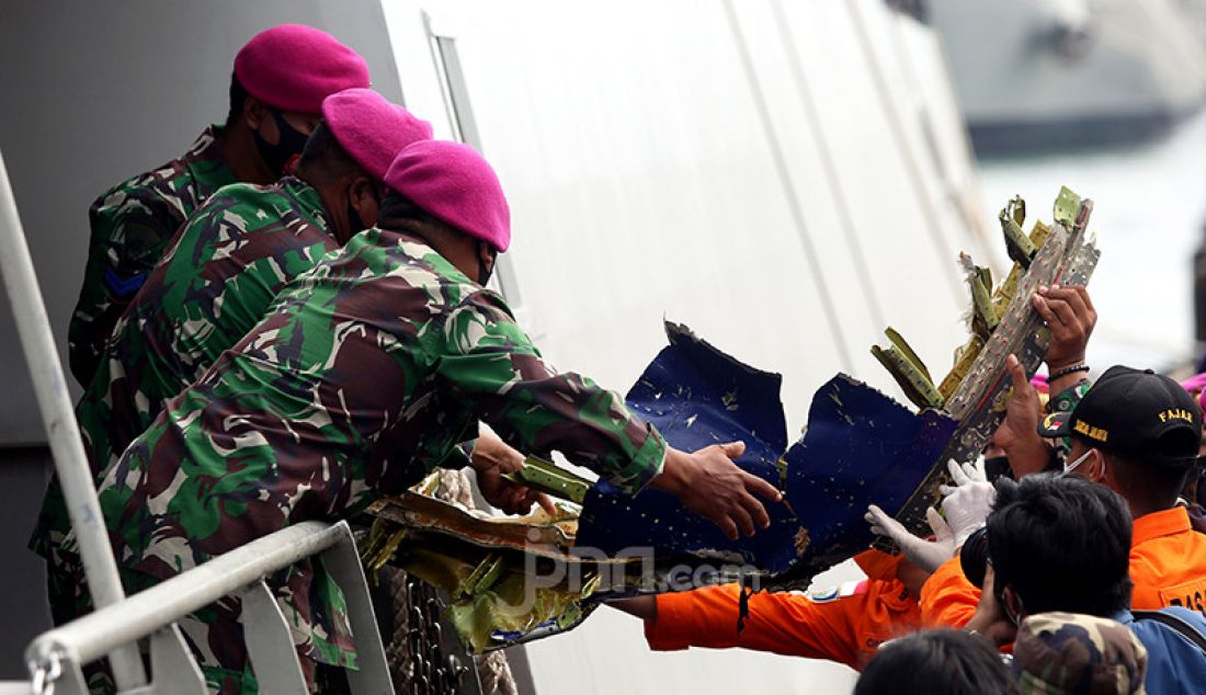 Anggota TNI dari kesatuan Marinir saat menurunkan serpihan pesawat Sriwijaya Air SJ 182 dan kantong jenazah yang berhasil dievakusi ke Dermaga, JICT 2, Jakarta, Minggu (10/1). - JPNN.com