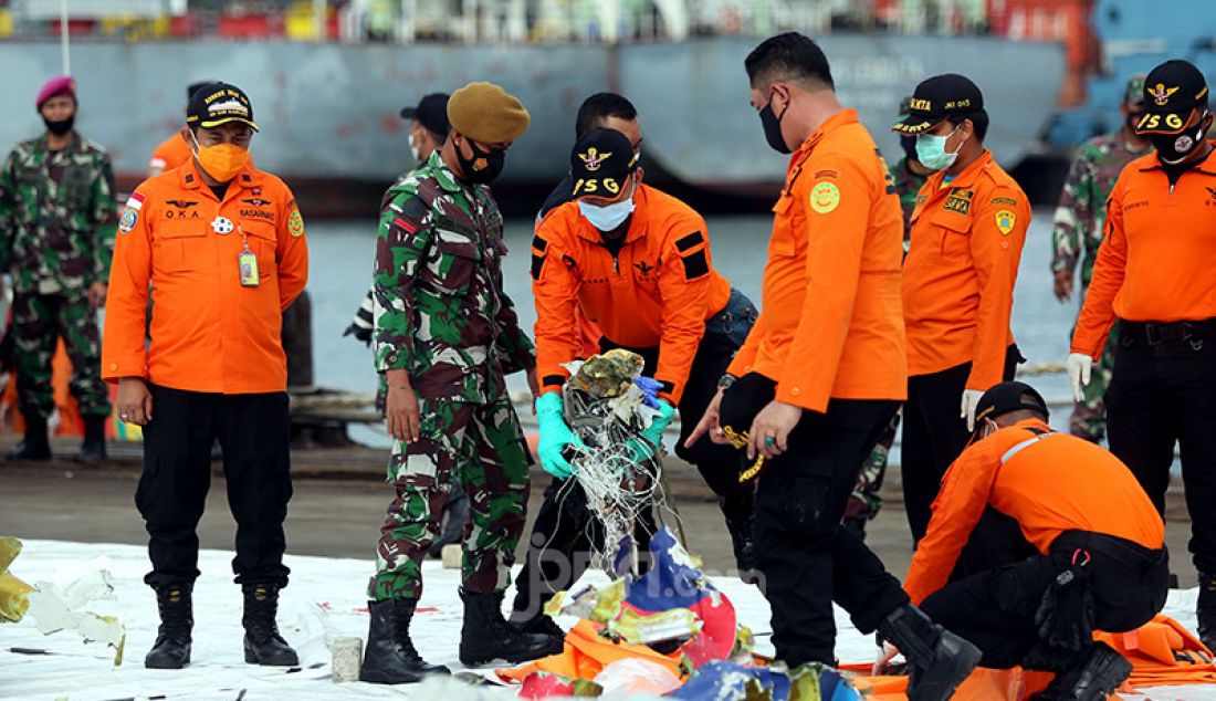 Petugas pencarian dan pertolongan memilah serpihan pesawat Sriwijaya Air SJ 182 yang dikumpulkan di Dermaga JICT 2, Jakarta Utara, Senin (11/1). - JPNN.com