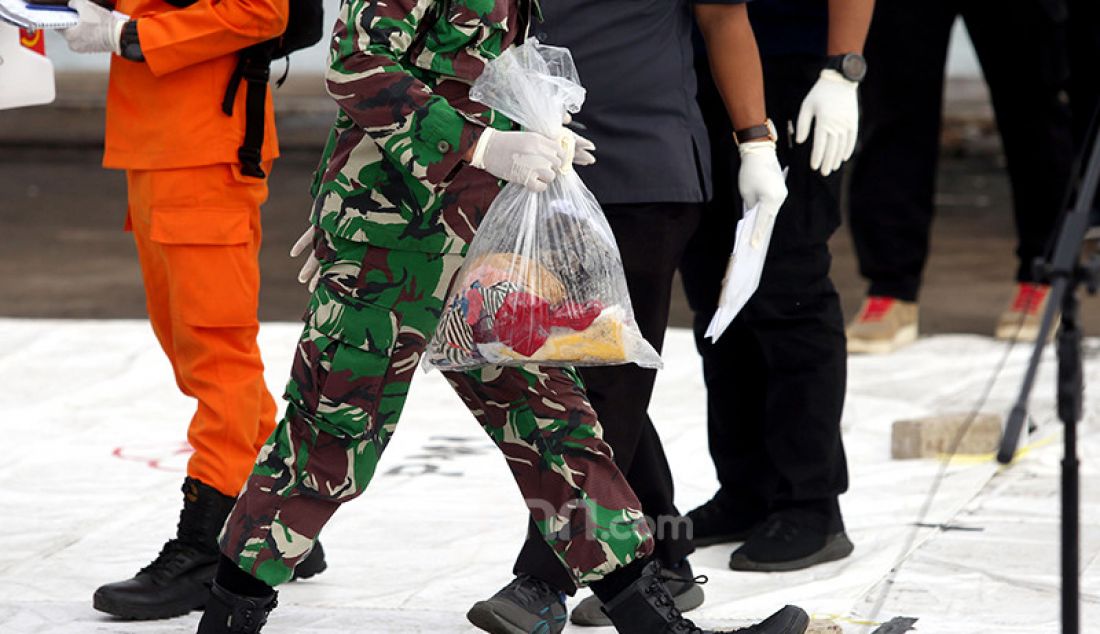 Petugas membawa kantong berisi barang milik penumpang pesawat Sriwijaya Air SJ182 yang dikumpulkan di Dermaga JICT 2, Jakarta Utara, Senin (11/1). - JPNN.com