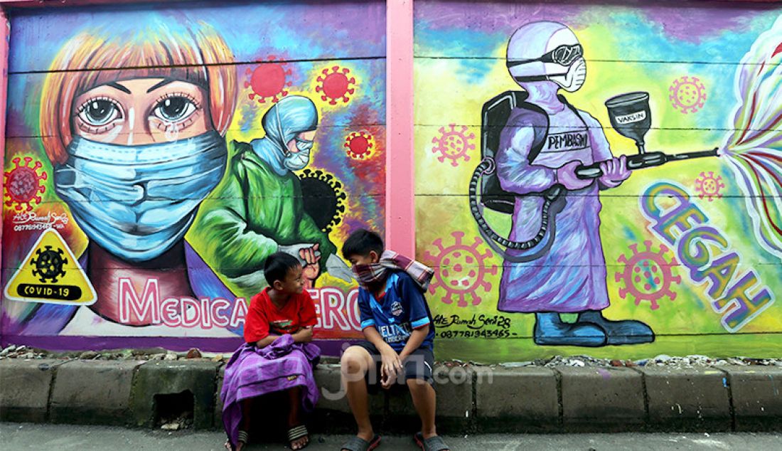 Dua bocah tengah duduk di depan mural bertema Covid-19 di kawasan Tanah Tinggi, Tangerang, Banten, Rabu (20/1). Mural tersebut untuk mengingatkan masyarakat akan bahaya Covid-19. - JPNN.com
