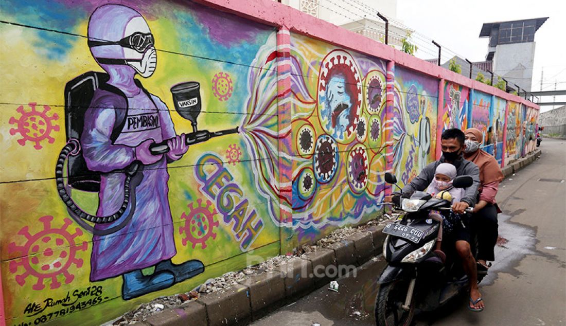 Warga melintas di samping mural bertema Covid-19 di kawasan Tanah Tinggi, Tangerang, Banten, Rabu (20/1). Mural tersebut untuk mengingatkan masyarakat akan bahaya Covid-19. - JPNN.com