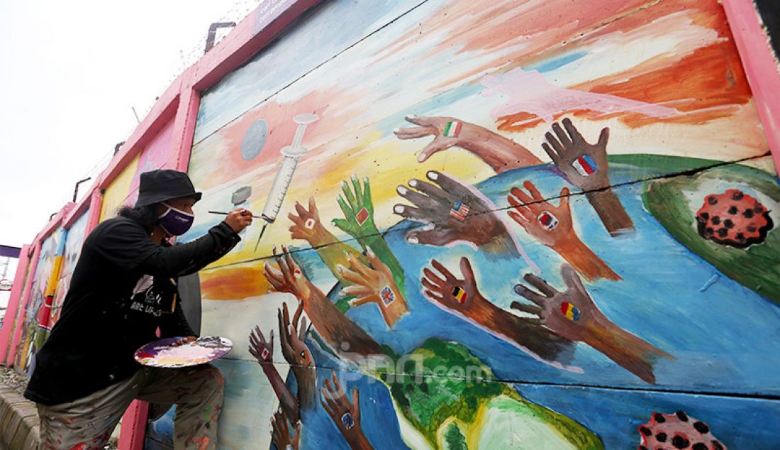 Pekerja seni tengah membuat mural bertema Covid-19 di kawasan Tanah Tinggi, Tangerang, Banten, Rabu (20/1). Mural tersebut untuk mengingatkan masyarakat akan bahaya Covid-19. - JPNN.com