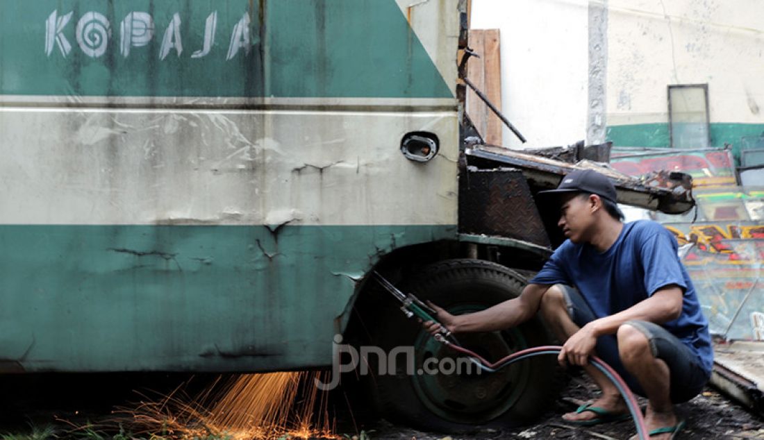 Pekerja membongkar bus Kopaja di kawasan Meruya, Jakarta Barat, Sabtu (30/1). Bus tersebut dijual ke pedagang besi tua lantaran tak dioperasikan lagi seiring program peremajaan Kopaja. - JPNN.com