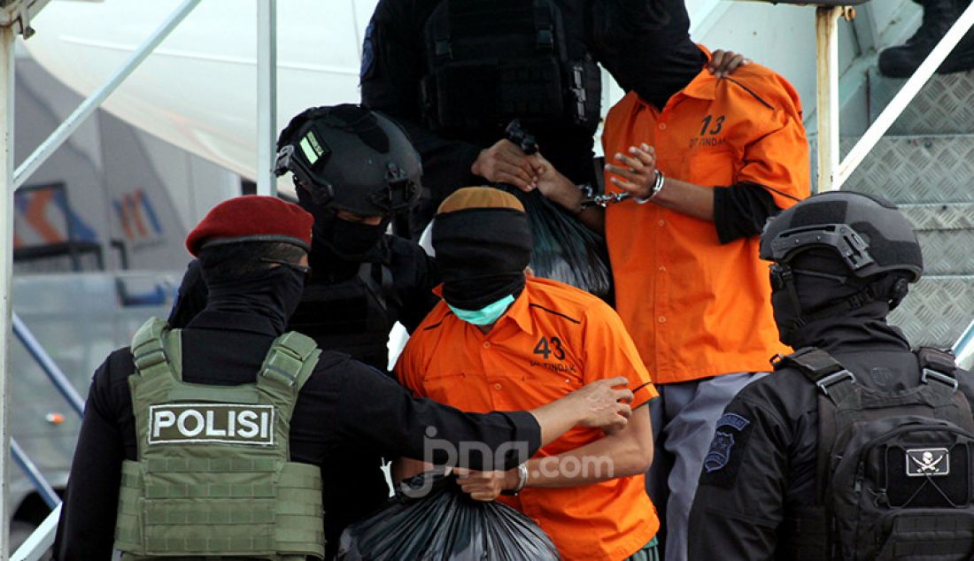 Anggota Detasemen Khusus 88 Antiteror Polri memegang terduga teroris menuruni tangga pesawat setibanya di Bandara Soekarno Hatta, Tangerang, Banten, Kamis (4/1). Polri memindahkan 26 terduga teroris dari Makassar dan Gorontalo ke Jakarta. - JPNN.com