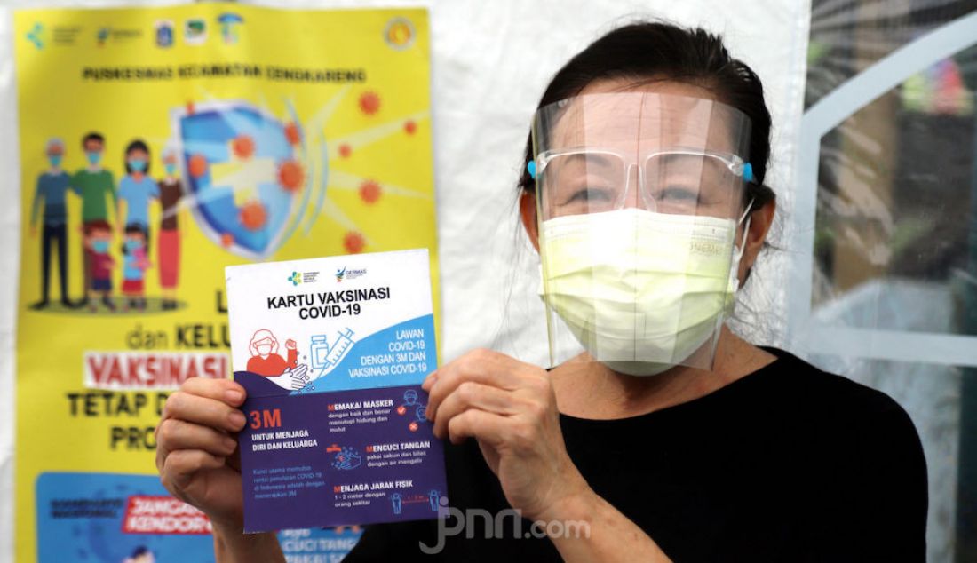 Seorang dokter berusia lanjut memperlihatkan kartu vaksinasi Covid-19 di Puskesmas Cengkareng, Jakarta Barat, Selasa (9/2). Pemerintah memprioritaskan tenaga kesehatan sebagai penerima vaksin Covid-19. - JPNN.com