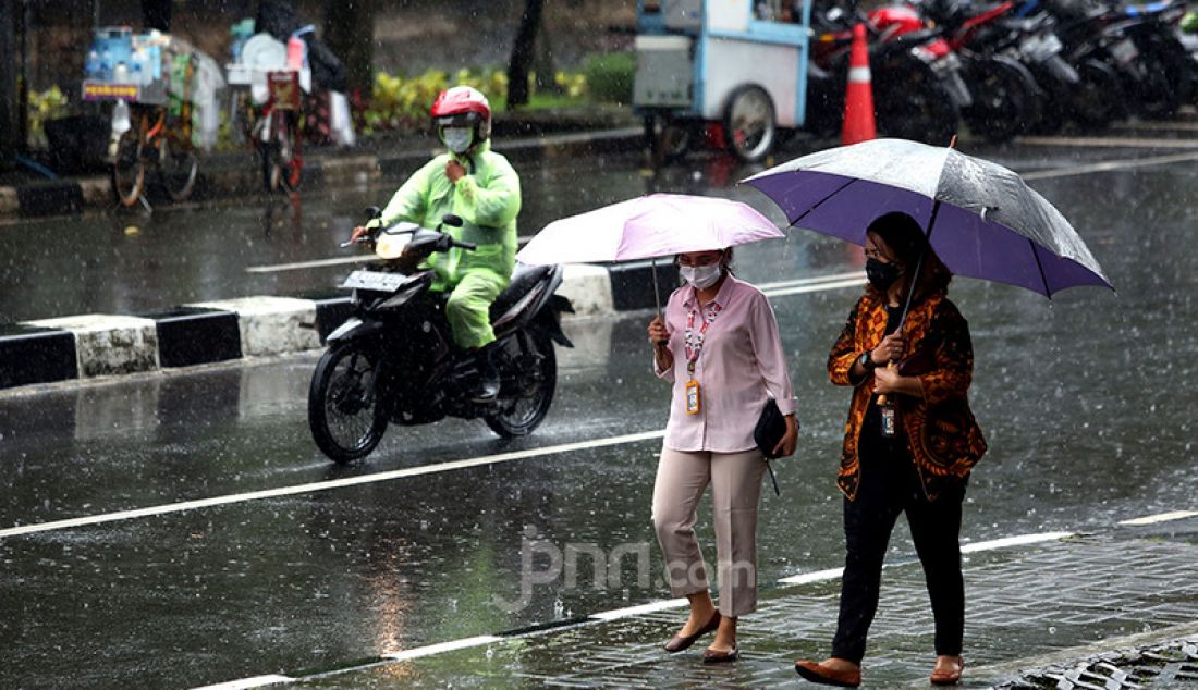 Warga menggunakan payung saat hujan mengguyur kawasan Kuningan, Jakarta Selatan, Selasa (16/2). Badan Meteorologi, Klimatologi, dan Geofisika (BMKG) memprakirakan cuaca ekstrem akan melanda wilayah Jabodetabek pada 15-21 Februari 2021. - JPNN.com
