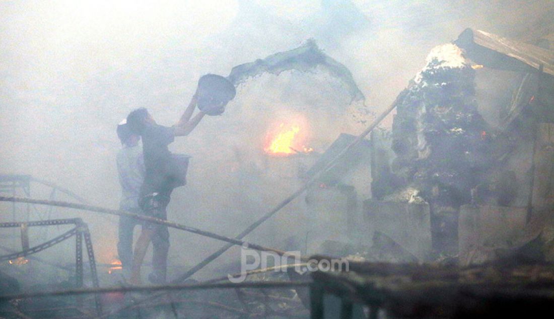 Pedagang mencoba memadamkan api yang melahap Pasar Kambing di Tanah Abang, Jakarta Pusat, Kamis (8/4). Sebanyak 17 unit branwir dan 85 personel pemadam kebakaran dikerahkan untuk memadamkan api yang menghanguskan ratusan lapak dan puluhan kios di Pasar Kambing. - JPNN.com