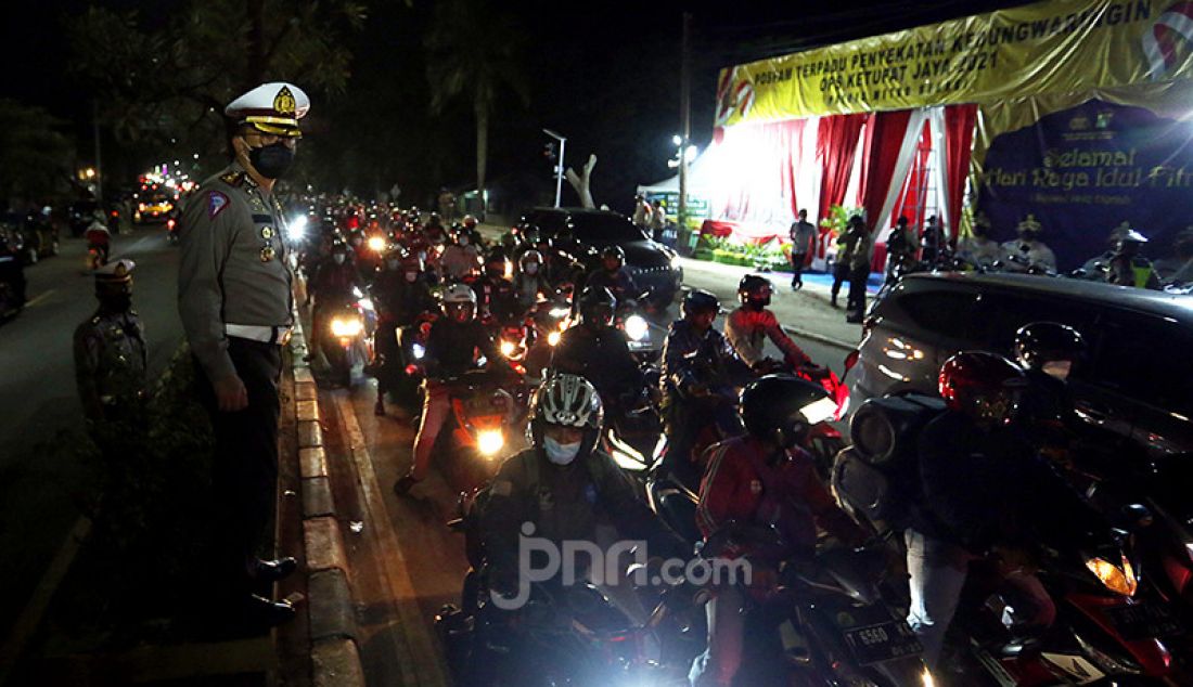 Aparat Polri memantau para pengendara sepeda motor di titik penyekatan perbatasan Kabupaten Bekasi dan Kabupaten Karawang, Jawa Barat, Senin malam (10/5). Penyekatan itu merupakan tindak lanjut atas kebijakan pemerintah tentang larangan mudik yang berlaku 6-17 Mei 2021. - JPNN.com