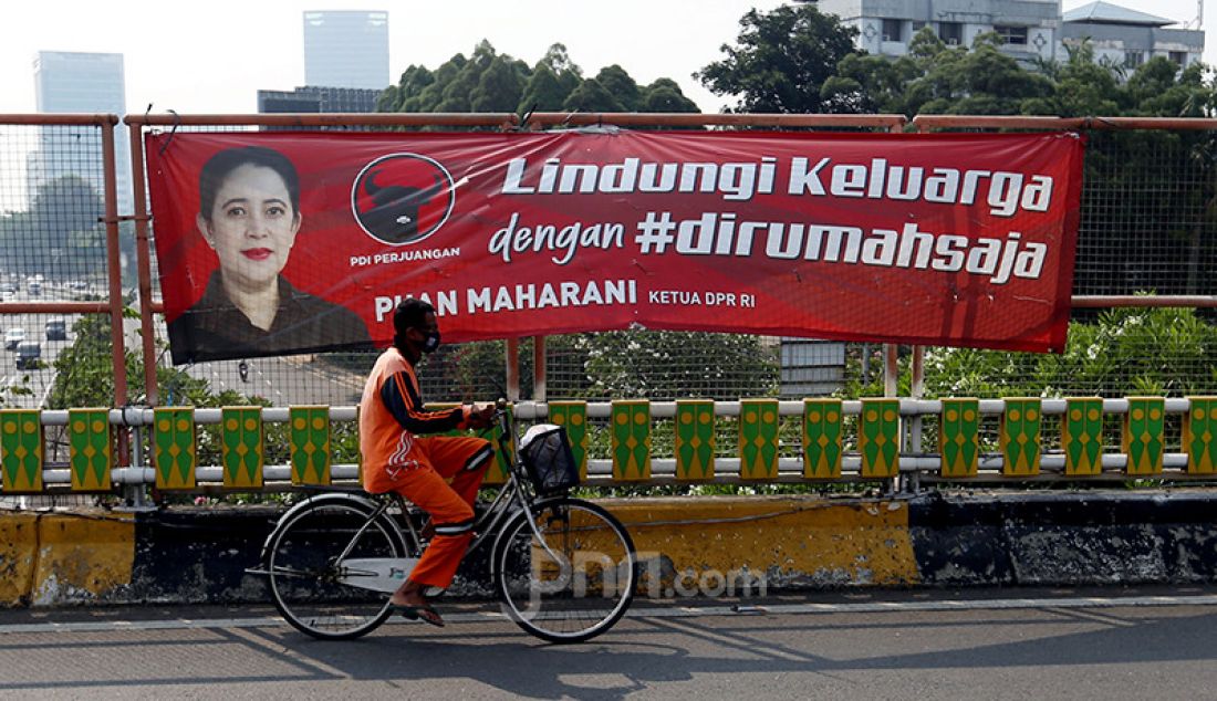 Pengendara sepeda melintas di depan spanduk bergambar Ketua DPR Puan Maharani di Flyover Ladogi, Jalan Jenderal Gatot Subroto, Jakarta Pusat, Jumat (30/7). - JPNN.com