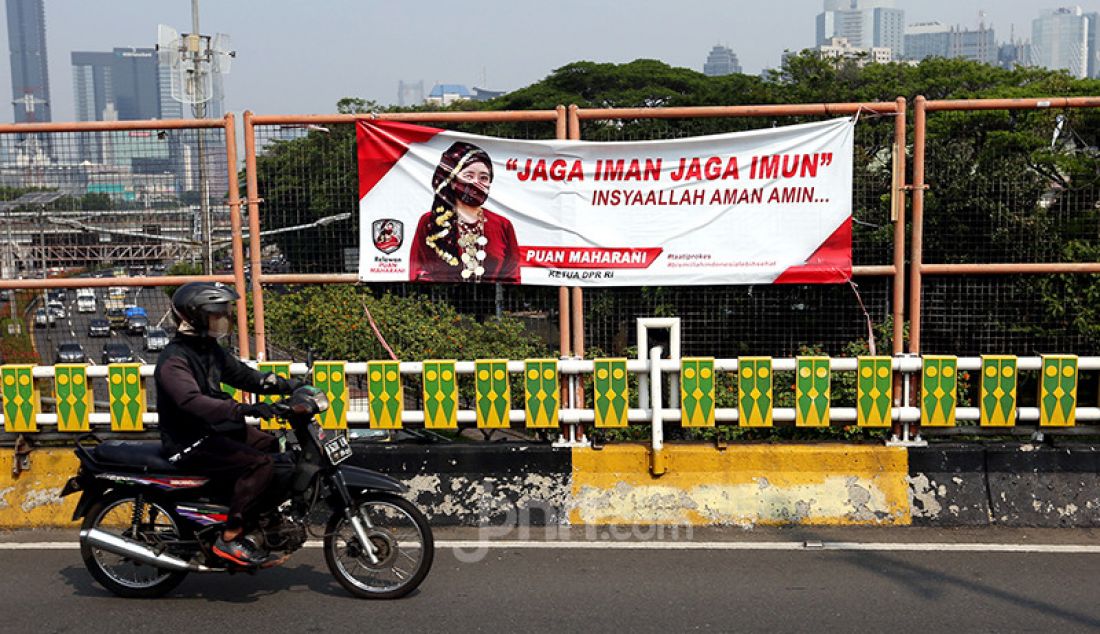 Pengendara sepeda melintas di depan spanduk bergambar Ketua DPR Puan Maharani di Flyover Ladogi, Jalan Jenderal Gatot Subroto, Jakarta Pusat, Jumat (30/7). - JPNN.com