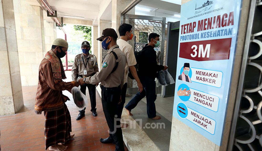 Pengurus Masjid Istiqlal memeriksa suhu tubuh warga yang hendak jumatan, Jumat (20/8). Masjid Istiqlal kembali menggelar Salat Jumat untuk umum dengan menerapkan pembatasan, antara lain, jumatan hanya bagi warga yang sudah divaksinasi dan jumlahnya dibatasi 25 persen dari kapasitas total. - JPNN.com