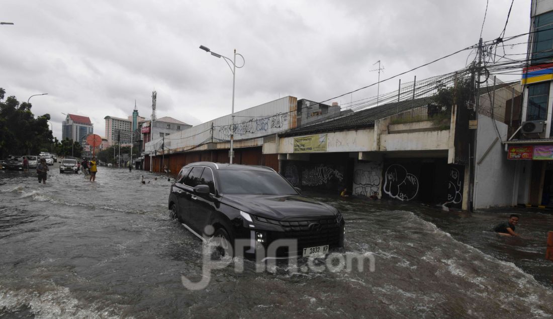 Warga melewati banjir pada ruas jalan Satrio, Grogol, jakarta Barat, Rabu (29/1). Hujan lebat yang melanda DKI Jakarta dan sekitarnya menyebabkan genangan di beberapa wilayah. Hingga siang ini, tercatat masih ada 34 RT dan 19 ruas jalan di Jakarta yang tergenang banjir. - JPNN.com