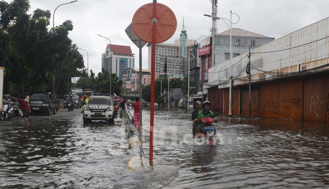 Warga melewati banjir pada ruas jalan Satrio, Grogol, jakarta Barat, Rabu (29/1). Hujan lebat yang melanda DKI Jakarta dan sekitarnya menyebabkan genangan di beberapa wilayah. Hingga siang ini, tercatat masih ada 34 RT dan 19 ruas jalan di Jakarta yang tergenang banjir. - JPNN.com