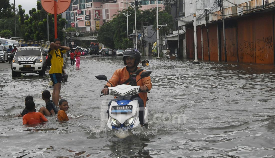 Warga melewati banjir pada ruas jalan Satrio, Grogol, jakarta Barat, Rabu (29/1). Hujan lebat yang melanda DKI Jakarta dan sekitarnya menyebabkan genangan di beberapa wilayah. Hingga siang ini, tercatat masih ada 34 RT dan 19 ruas jalan di Jakarta yang tergenang banjir. - JPNN.com