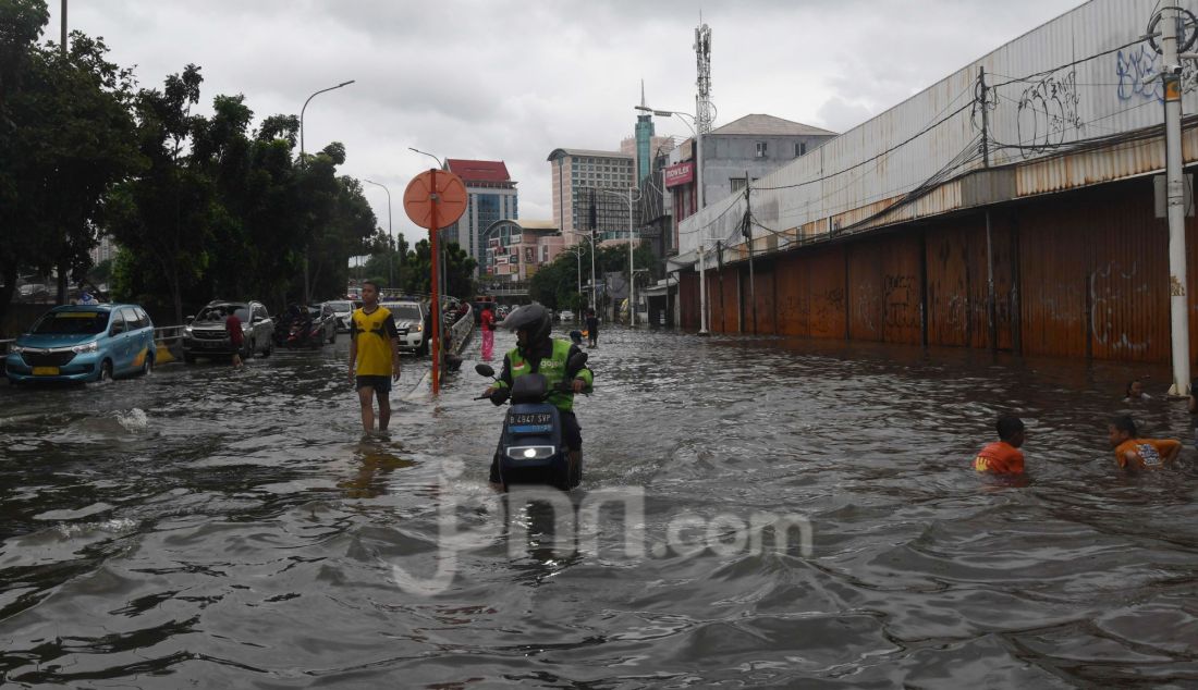 Warga melewati banjir pada ruas jalan Satrio, Grogol, jakarta Barat, Rabu (29/1). Hujan lebat yang melanda DKI Jakarta dan sekitarnya menyebabkan genangan di beberapa wilayah. Hingga siang ini, tercatat masih ada 34 RT dan 19 ruas jalan di Jakarta yang tergenang banjir. - JPNN.com