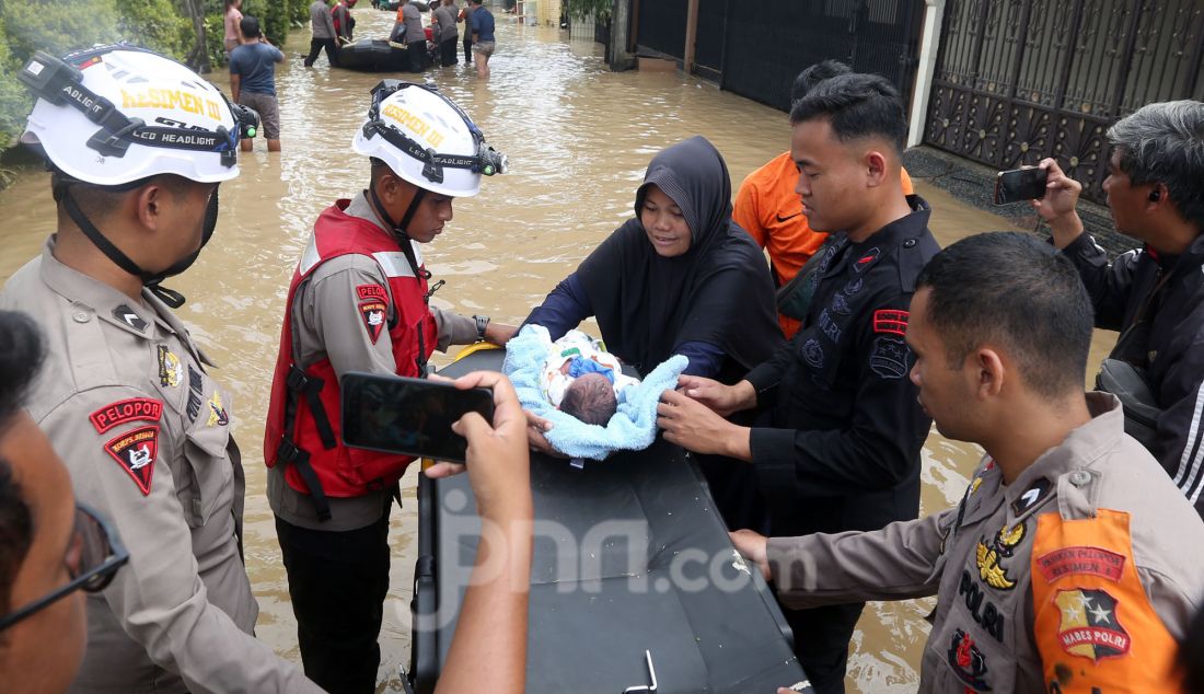 Tim gabungan BPBD mengevakuasi korban banjir di perumahan Vila Nusa Indah 3, Gunung Putri, Kabupaten Bogor, Jawa Barat, Selasa (4/3). Banjir yang terjadi di kawasan perbatasan Bogor dan Bekasi akibat luapan kali Cikeas dan Cileungsi menyebabkan ketinggian air hingga 4 meter di rumah warga. - JPNN.com