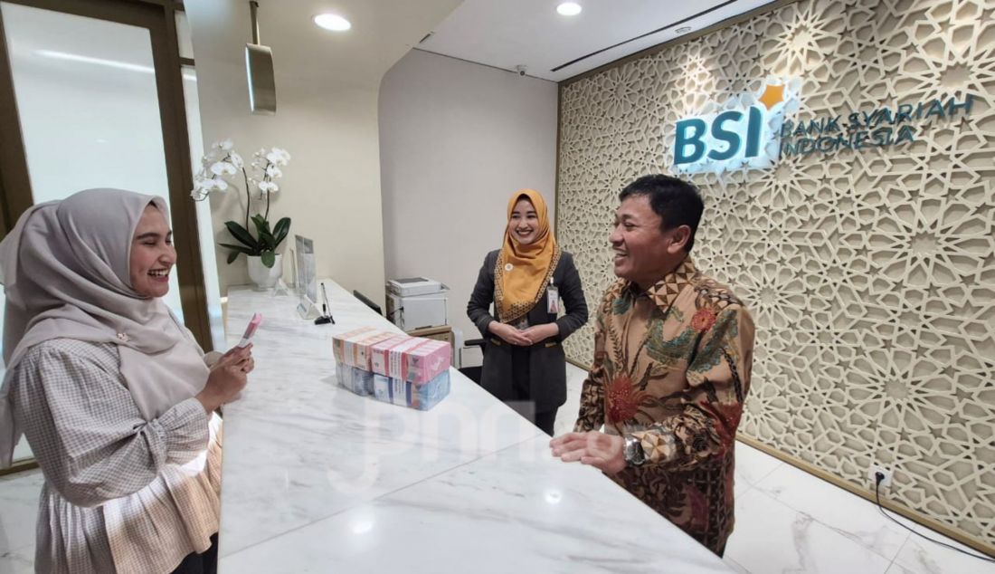 Wakil Direktur Utama BSI Bob T Ananta (kiri) menyapa nasabah (kanan) yang sedang bertransaksi di PT Bank Syariah Indonesia Tbk (BSI) Kantor Cabang The Tower Jakarta, Kamis (13/3). BSI mengalokasikan kebutuhan uang tunai jelang Idulfitri sebesar Rp42,88 triliun mengalami peningkatan sekitar 14% dibandingkan periode ramadan tahun lalu. - JPNN.com